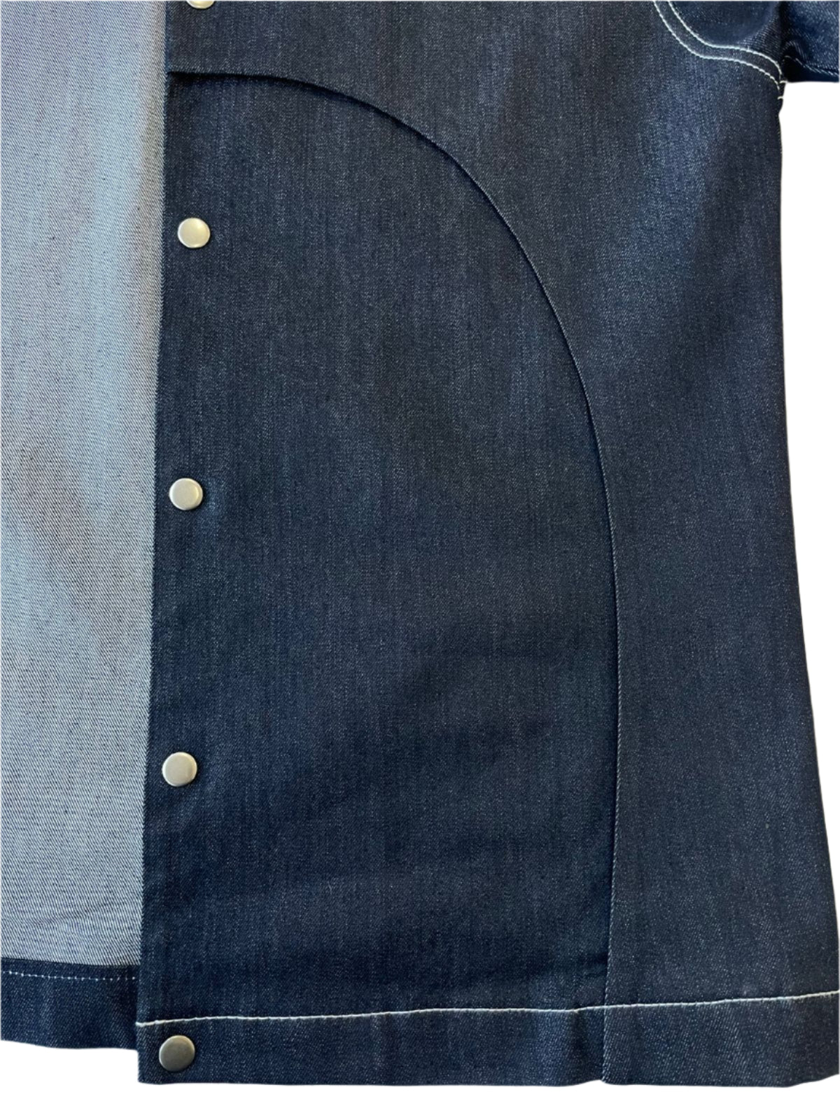 Close-up of a dark denim jacket with gold press studs on a white background