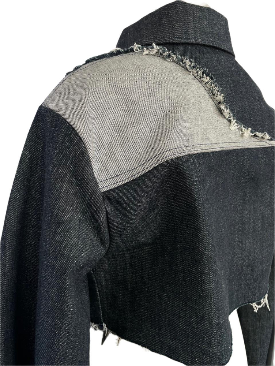 Back view of a dark denim jacket with frayed edges on a mannequin against a white background
